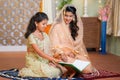 indian muslim woman helping kid to read quran before festing food during ramdan festival at home - concept of festival