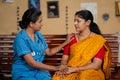 Indian nurse at home giving confidence or consoling by holding hands of sick woman at home - concept of caregiver