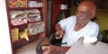 An indian old man cutting ground nuts at pan shop betel leaf making purpose