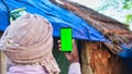 Old Indian man taking selfie and showing a green screen cell phone with rural village life concept background Royalty Free Stock Photo