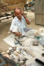 Indian old man talking on his mobile phone in his cobbler shop