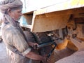 an indian old mechanic putting grease oil into the truck parts during oiling work at automobile service center in India dec 2019