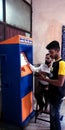 An indian passenger collecting tickets from automatic ticket vending machine counters