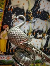 indian peacock sculpture artifact in silver metal with indian folk art is in background