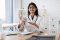 Indian physician holding glass of liquid at office room