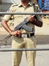 Indian police man stand with weapon behind barricade on the road