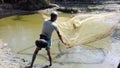 A Indian poor fisherman throwing his net in small lake to catch fishes