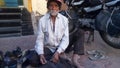 Indian poor shoe maker making shoes on road side .