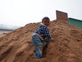an indian poor village kid climbing on sand stock during construction work in India dec 2019