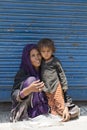 Indian poor woman with children begs for money from a passerby on the street in Srinagar, India Royalty Free Stock Photo