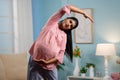 Indian pregnant woman doing stretching exercise or yoga asana at home - concept of healthy lifestyle, maternity workout Royalty Free Stock Photo