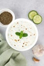 Indian raita sauce with yogurt, cucumber and herbs on a gray background. Top view. Indian food. Greek tzatziki sauce. Royalty Free Stock Photo