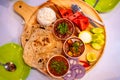 Indian rice and bread served wirh chicken curry and paneer curry on a pan along with fruits and salad top view