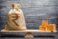 Indian rupee INR symbol money bag and a bunch of boxes on scales. Trade exchange balance. Import and export, economic processes. Royalty Free Stock Photo