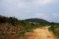 A Indian rural village soily road landscape with blue sky and white clouds background passing beside a small hill or hillock. Royalty Free Stock Photo