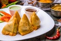 Indian samosa with vegetables on white plate and blue wooden table