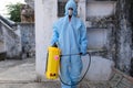 Indian sanitary worker in a protective suit conducting disinfection of a school during COVID-19