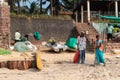 Indian sanitation workers cleaning the trash with brooms at the tourist beach in Sinquerim