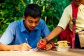 Indian school boy writing on notepad doing homework , looking concentration . His friend with backpack sits on table and Royalty Free Stock Photo