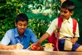 Indian school boy writing on notepad doing homework , looking concentration . His friend with backpack sits on table and Royalty Free Stock Photo