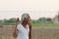 An Indian senior aged man farmer thinking about something while holding a shovel in his hand at sunset Royalty Free Stock Photo