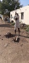 An Indian senior citizen chopping the wood for his wife to prepare food in kitchen.