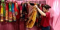 an indian shopkeeper girl holded traditional women outfits at garment store