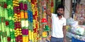 an indian shopkeeper selling artificial flowers chain at devotional item store Royalty Free Stock Photo