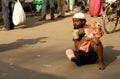 Indian sick beggar seeking help on a busy road.