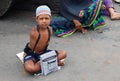 Indian sick and handicapped beggar seeking help on a busy road.