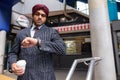 Indian Sikh businessman checking smart watch and holding coffee Royalty Free Stock Photo