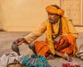 An Indian snake charmer touching a king cobra.