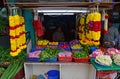 Indian stall selling different flower buds on the table basket, green lime, leaves and colourful garland nearby Hindu temple