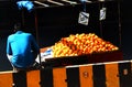 Indian Street food vendor sell orange fruits on mobile cart on side of a busy road