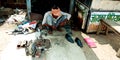 An Indian street shoemaker repairing black boot