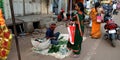 indian street shopkeeper selling fresh mango leaves to the lady customer on road