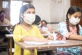 Indian Students wearing face masks sitting with social distancing at a classroom as school reopen during covid19