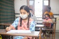 Indian Students wearing face masks sitting with social distancing at a classroom as school reopen during covid19