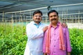 Indian supportive agro scientist with village farmer at green house looking at camera - concept of support