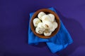 Indian Sweet or Dessert - Rasgulla, Famous Bengali sweet in clay bowl with blue napkin on violet background