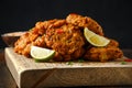 Indian takeaway food, spicy onion bhajis served with chili yoghurt dip and lime wedges on wooden board Royalty Free Stock Photo