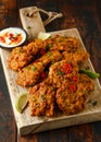 Indian takeaway food, spicy onion bhajis served with chili yoghurt dip and lime wedges on wooden board Royalty Free Stock Photo