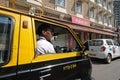 Indian taxi driver in old taxi in Mumbai