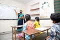 Indian teacher and students wearing face masks maintaining social distancing study in classroom back at school during covid19