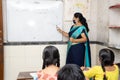 Indian teacher and students wearing face masks maintaining social distancing study in classroom back at school during covid19