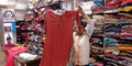 an indian textile seller presenting women dress in orange colour at showroom