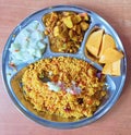 An Indian thaali containing sweet khichadi, paneer (cottage cheese) curry, mangoes and cucumber-curd salad