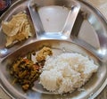 Indian thaali for lunch containing white rice, papadam, chutney and some fried mixed vegetables