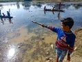 an indian village boy pointing wooden stick towards water lake in India dec 2019