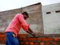an indian village construction worker applying raw materials for brick wall creation at site in India dec 2019